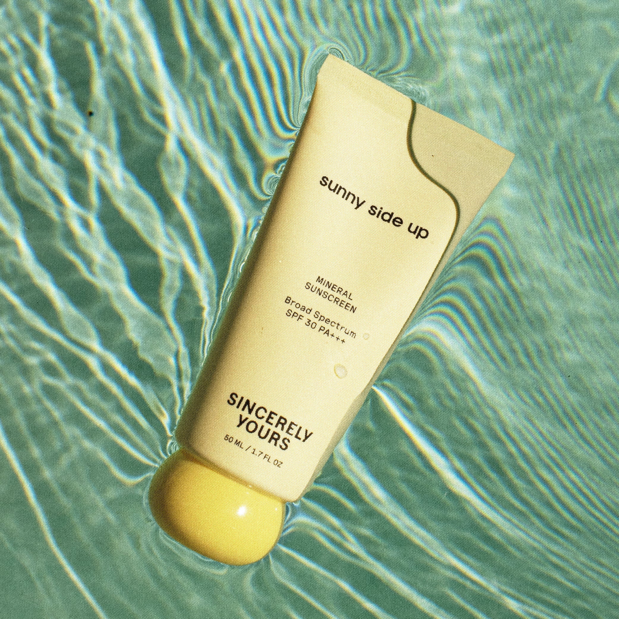 Sunscreen bottle labeled 'sunny side up' on a water surface